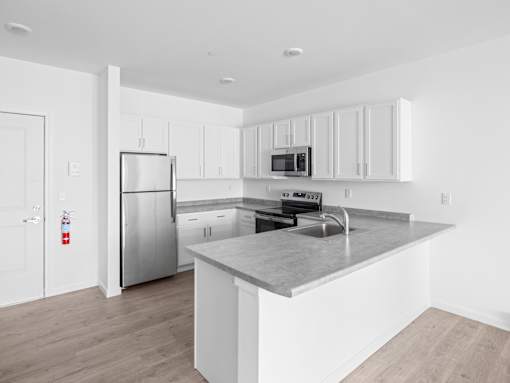 A kitchen with a stainless steel refrigerator, microwave, and sink.
