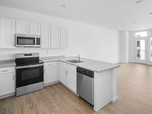 A kitchen with white cabinets and a wooden floor.