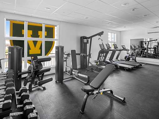 A gym with a variety of equipment including weights, benches, and treadmills.