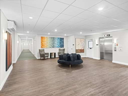 A spacious waiting room with a round black sofa and chairs.