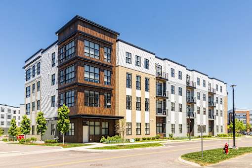 A modern apartment building with a mix of wood and white exterior walls.