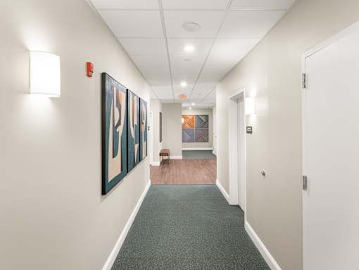A hallway with a painting on the wall and a bench in the middle.