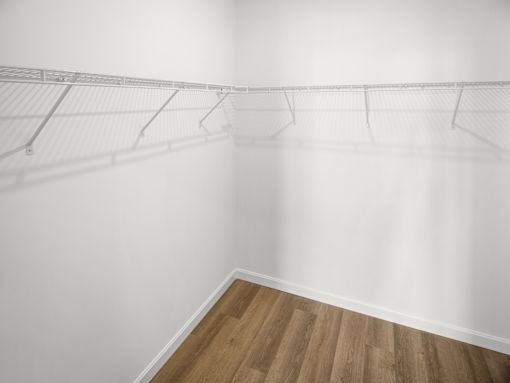A white wall with a wooden floor and a wire shelf.
