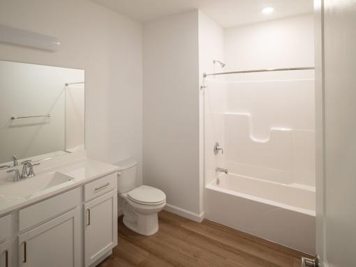 A white bathroom with a toilet, sink, and bathtub.