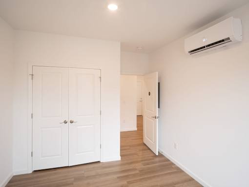 A room with a white door and a white wall with a window.