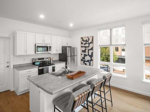 A kitchen with white cabinets and a grey countertop.