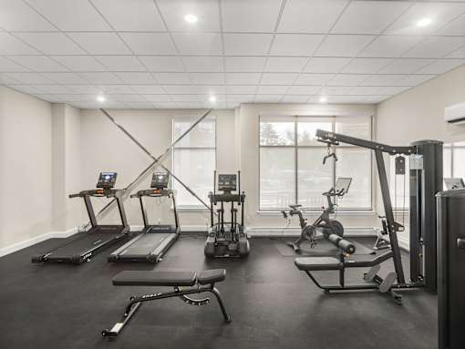 A gym with treadmills, elliptical machines, and a weight machine.