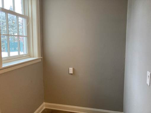 A room with a window and a light switch on the wall.
