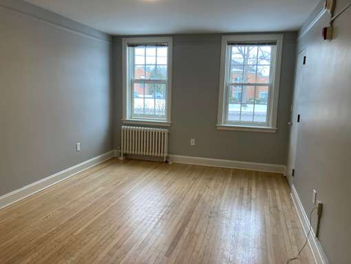 A room with wooden floors and two windows.