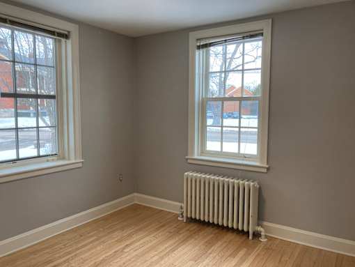 A room with a window and a radiator on the floor.