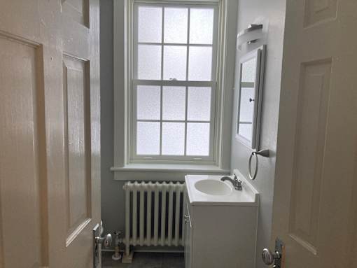 A white sink in a small bathroom with a window.
