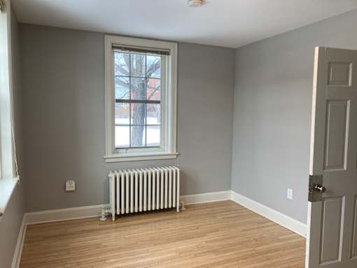 A room with a window and a radiator on the floor.