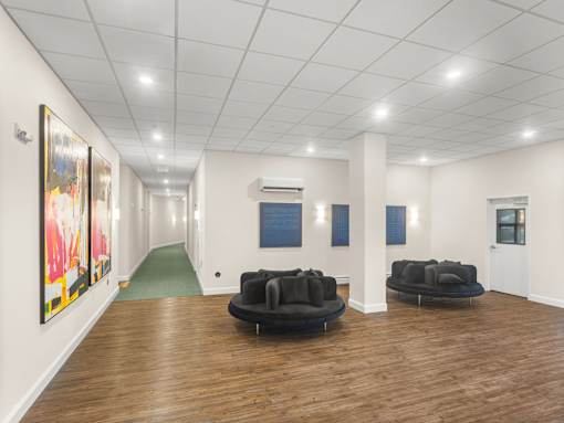 A long hallway with a green carpet and two black couches.