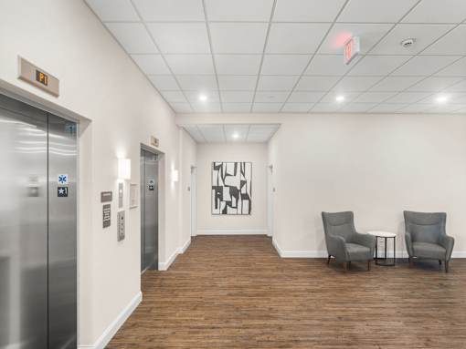 A hallway with two elevators and a painting on the wall.