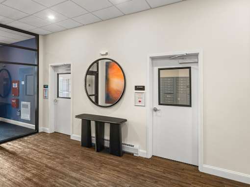 A hallway with a round mirror and a bench.