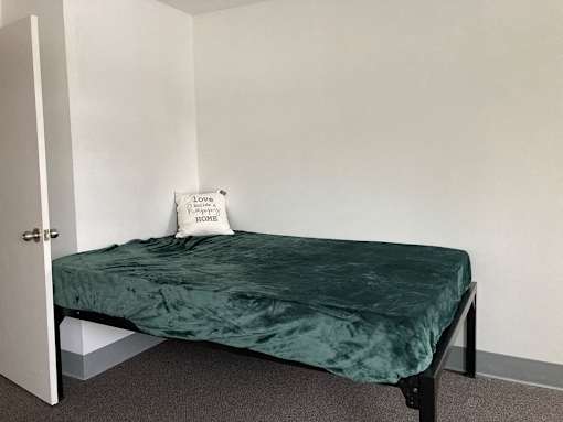 a small bed in a room with a green blanket