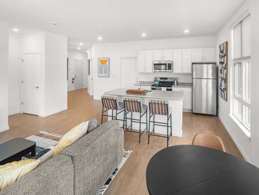 A modern kitchen with a grey couch and a black table.