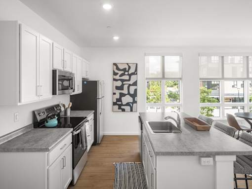 A modern kitchen with a black and white artwork on the wall.
