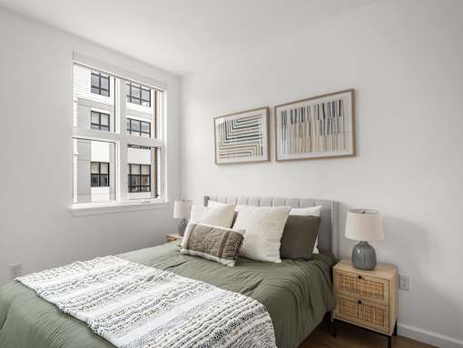 A bedroom with a bed, nightstand, and two framed artworks on the wall.