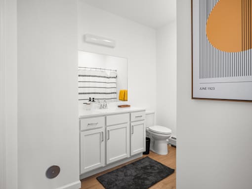 A bathroom with a toilet, sink, and a painting on the wall.