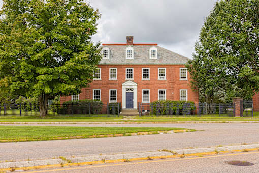 A red brick house with a black fence in front.