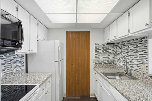 A kitchen with a wooden door and a sink.