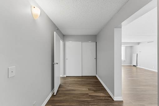 A long, narrow hallway with white walls and wood flooring.