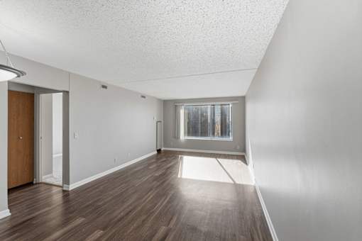 A room with a wooden floor and a window with a view of a city.