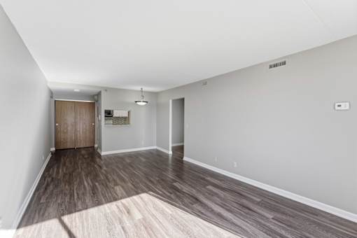 A room with a wooden floor and a door on the left side.