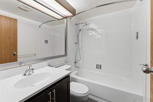 A white bathroom with a toilet, sink, and bathtub.