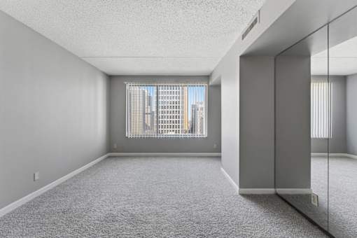 A spacious room with a large window and a carpeted floor.