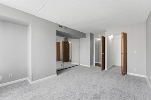 A spacious room with a carpeted floor and white walls.
