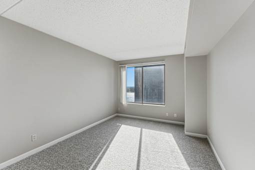 A room with a carpeted floor and a window.