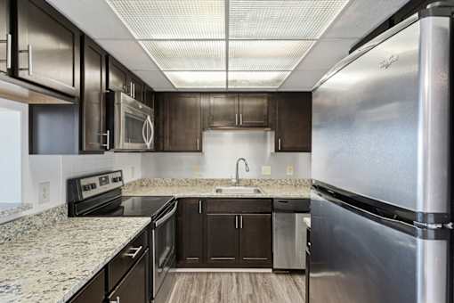 A modern kitchen with dark wood cabinets and stainless steel appliances.