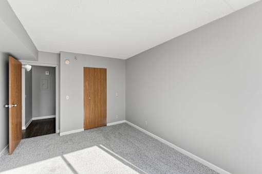 A room with a carpeted floor and two doors.