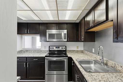 A modern kitchen with dark brown cabinets and stainless steel appliances.