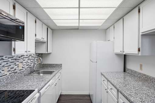 A kitchen with white cabinets and a granite countertop.