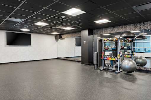 A spacious gym with a variety of equipment including a treadmill, weights, and a television.