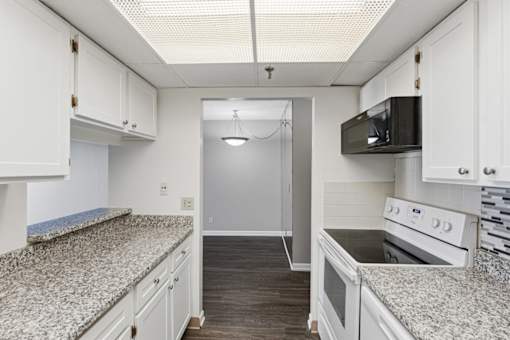A kitchen with granite countertops and white cabinets.