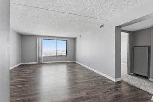 A spacious room with wooden flooring and a large window.