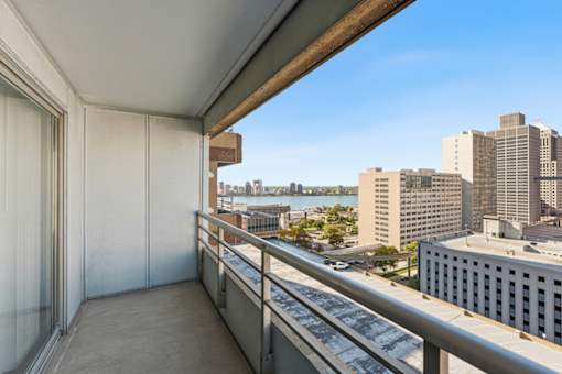 A balcony with a metal railing overlooks a cityscape.