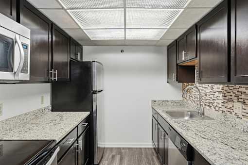 A kitchen with black cabinets and granite countertops.