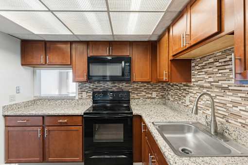 A kitchen with a black oven and wooden cabinets.