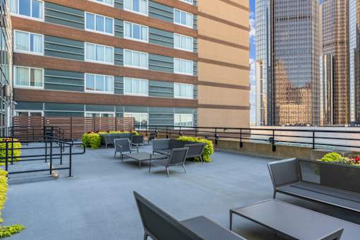 A patio with grey furniture and plants in front of a building.