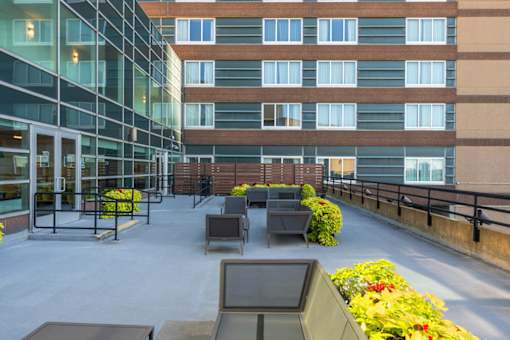A modern building with a glass facade and a balcony with furniture.