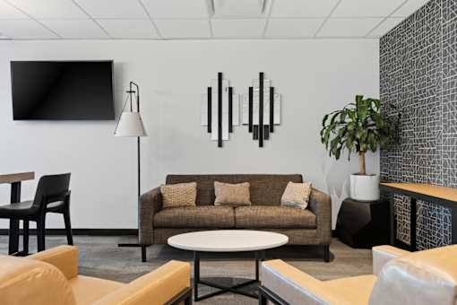 A modern living room with a couch, chairs, and a television.