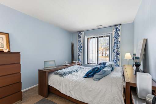 A bedroom with a bed, nightstand, and a window with curtains.