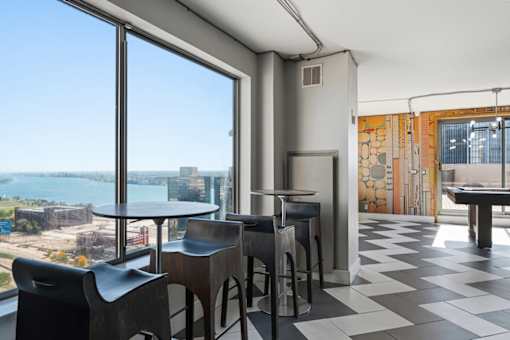 A room with a table and chairs with a view of the city.