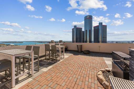 A rooftop patio with a table and chairs overlooking a city skyline.