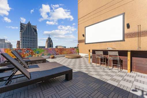 A rooftop patio with a table and chairs and a blank billboard.